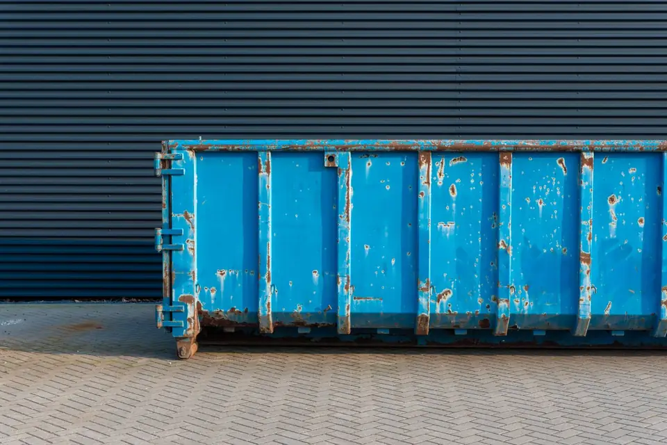 Benne de chantier bleue posée devant un bâtiment